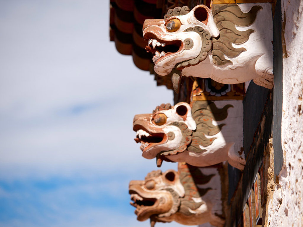 Houten drakenkoppen aan de dakrand van een boeddhistisch klooster in Bhutan, tijdens groepsrondreis Sikkim en Bhutan.