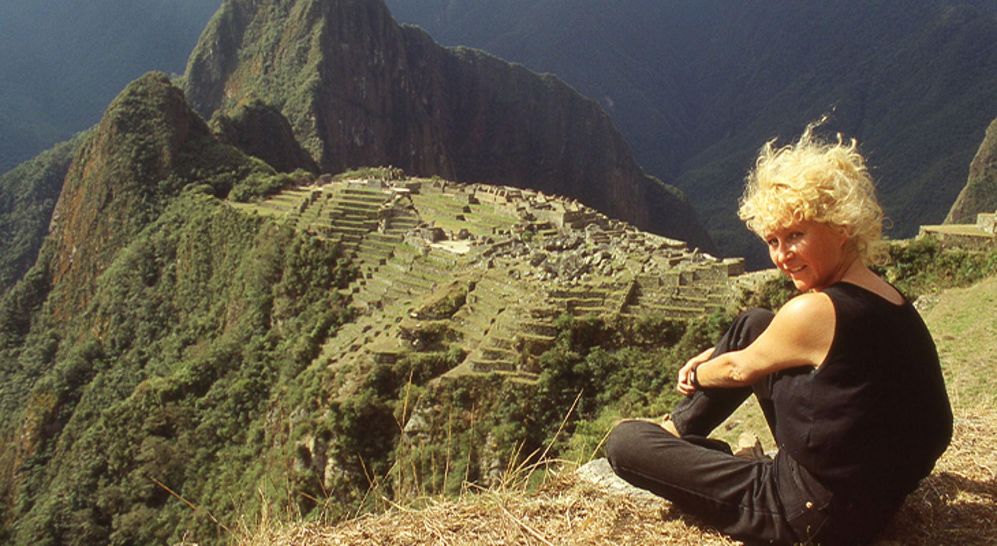 Mieke in Peru Vrouw zit op een berghelling met uitzicht op Machu Picchu in Peru.