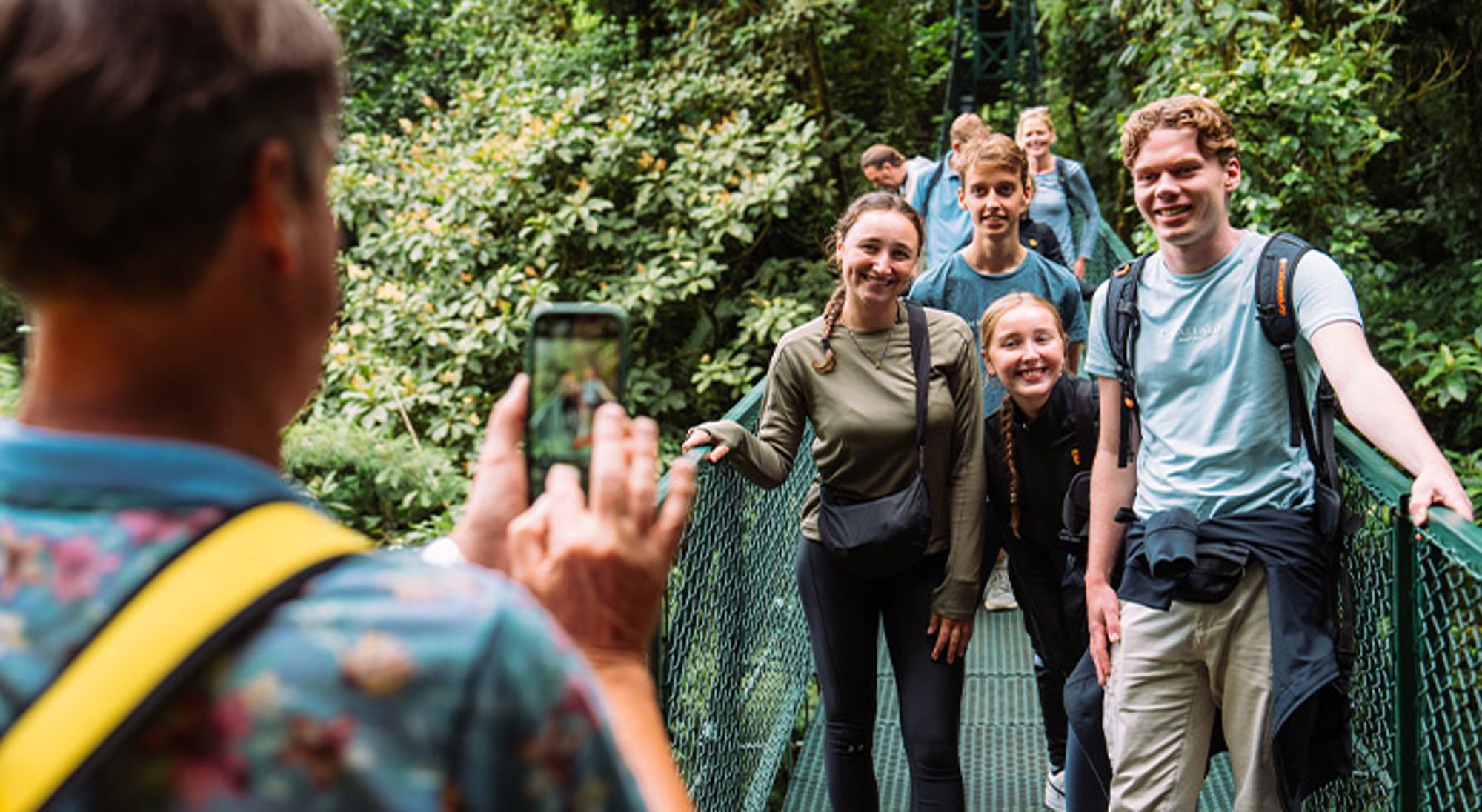Kinderen Costa Rica Gezin maakt een wandeltocht door het regenwoud en poseert op een hangbrug tijdens een Sawadee familiereis.