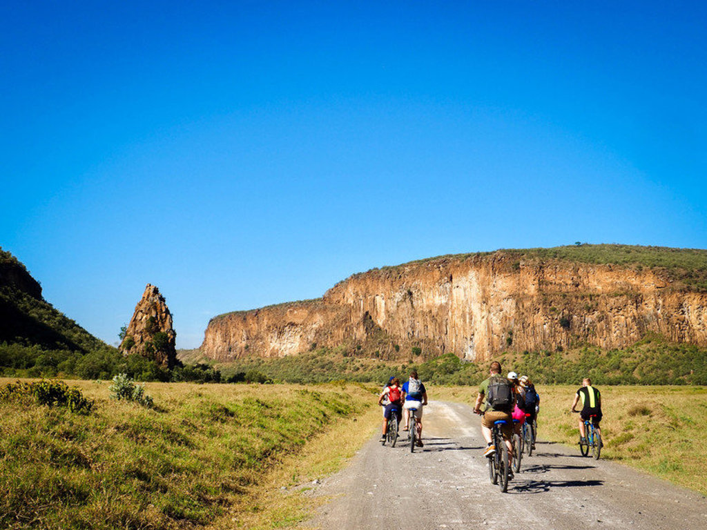 Groep 22-35ers fietst door de savanne langs rotskliffen tijdens rondreis Kenia & Tanzania.