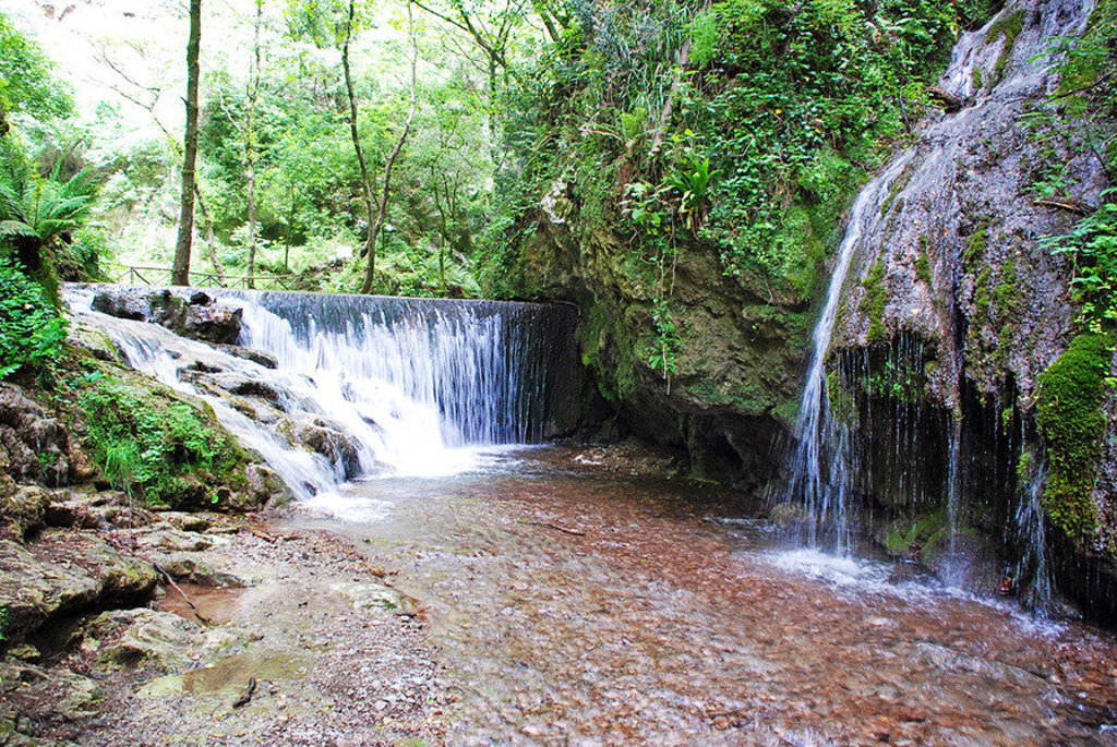Waterval in een groene kloof in Zuid-Italië, met helder water dat over rotsen stroomt.