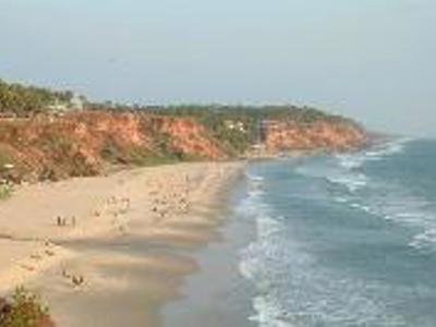 Rode kliffen langs een breed zandstrand aan de kust van Zuid-India, met golven van de Arabische Zee.