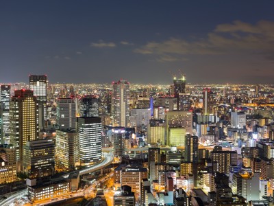 Verlichte skyline van Osaka bij avond, met wolkenkrabbers en snelwegen tijdens Route Japan 16 dagen.