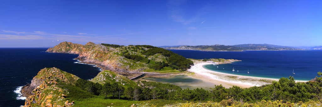 Panorama van een groene kust met wit zandstrand en blauwe zee tijdens familiereis Spanje & Portugal.