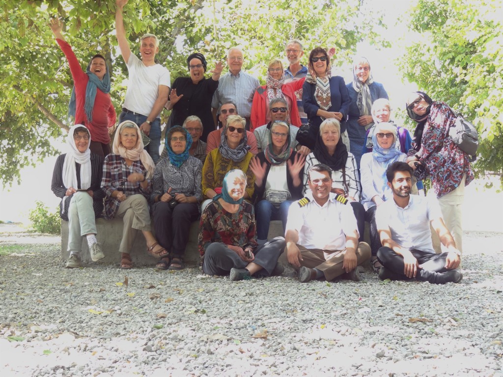 Groepsfoto van reizigers tijdens een rondreis Iran, zittend en staand onder bomen.