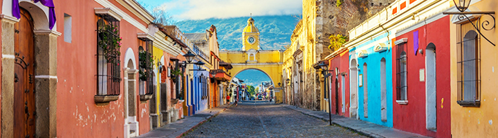 Kleurrijke straat in Antigua Guatemala met de Arco de Santa Catalina en de vulkaan Agua op de achtergrond.