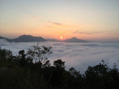Zonsopkomst boven een zee van mist en bergtoppen in Thailand.