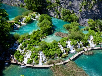 Houten wandelpad langs watervallen en turquoise meren in Nationaal Park Plitvicemeren, Kroatië.