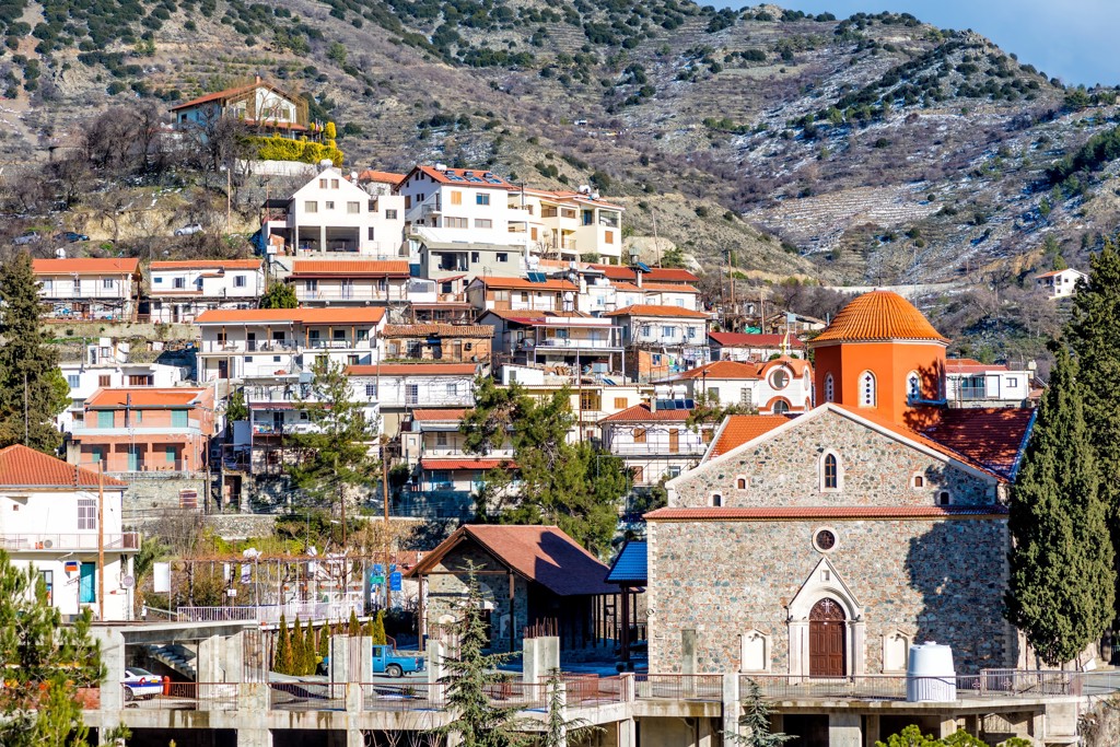 Bergdorp op Cyprus met traditionele huizen en een stenen kerk met oranje koepel, tijdens familiereis Cyprus kort.