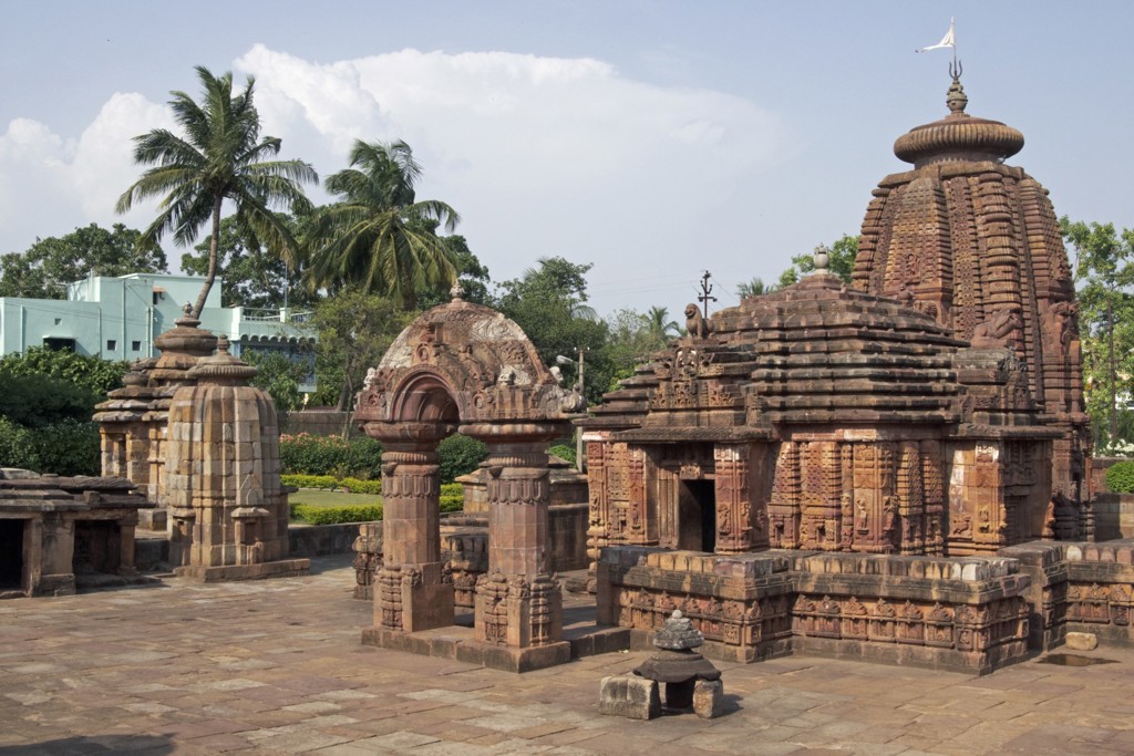 Hindoetempelcomplex in Orissa, India, met rijk versierde zandstenen toren en palmbomen op de achtergrond.