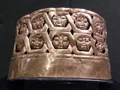 Gouden hoofdtooi met reliëfgezichten uit Noord-Peru, tentoongesteld in een museum.