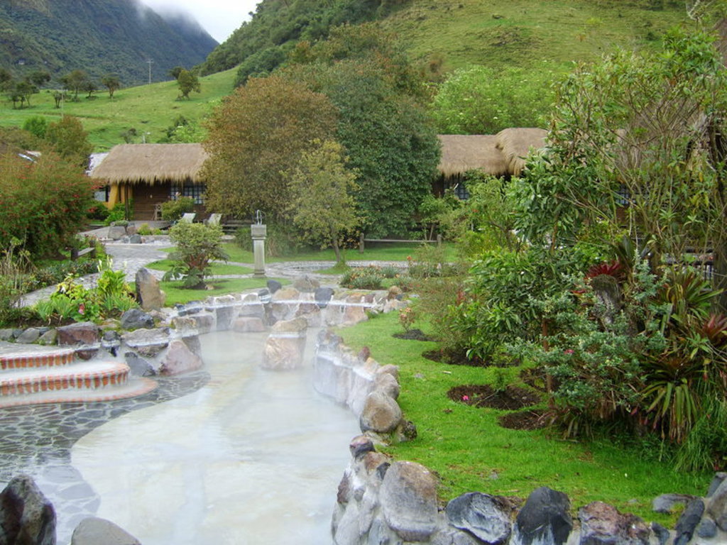Warmwaterbron met natuurlijke baden en rieten lodges in het groene Andeslandschap van Ecuador.