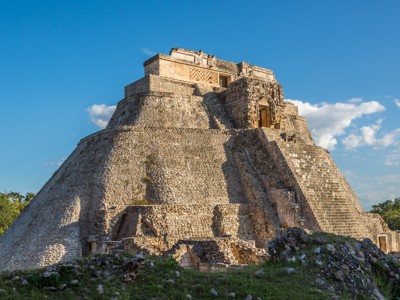 Piramide van Uxmal in Yucatán, Mexico, met stenen trappen onder een blauwe lucht.