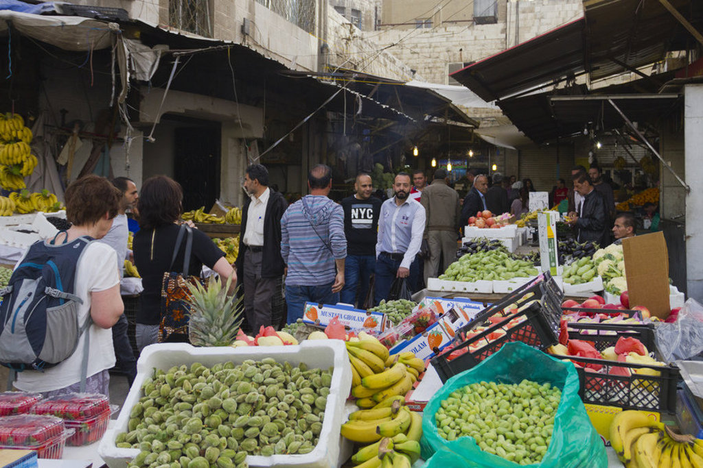 Drukke groente- en fruitmarkt in Jordanië met kraampjes vol bananen, druiven en vijgen.
