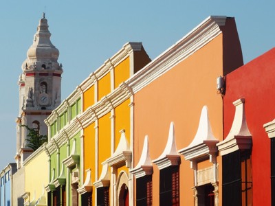 Kleurrijke gevels in een Mexicaanse straat met kerktoren op de achtergrond, route Mexico.