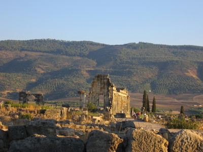 Romeinse ruïnes van Volubilis in Marokko, met stenen bogen en heuvels op de achtergrond.