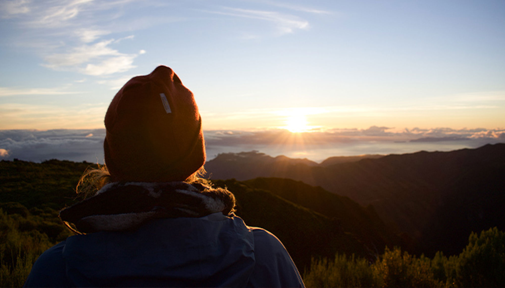 Carolien op Madeira Wandelaar kijkt naar de zonsopgang boven een berglandschap.