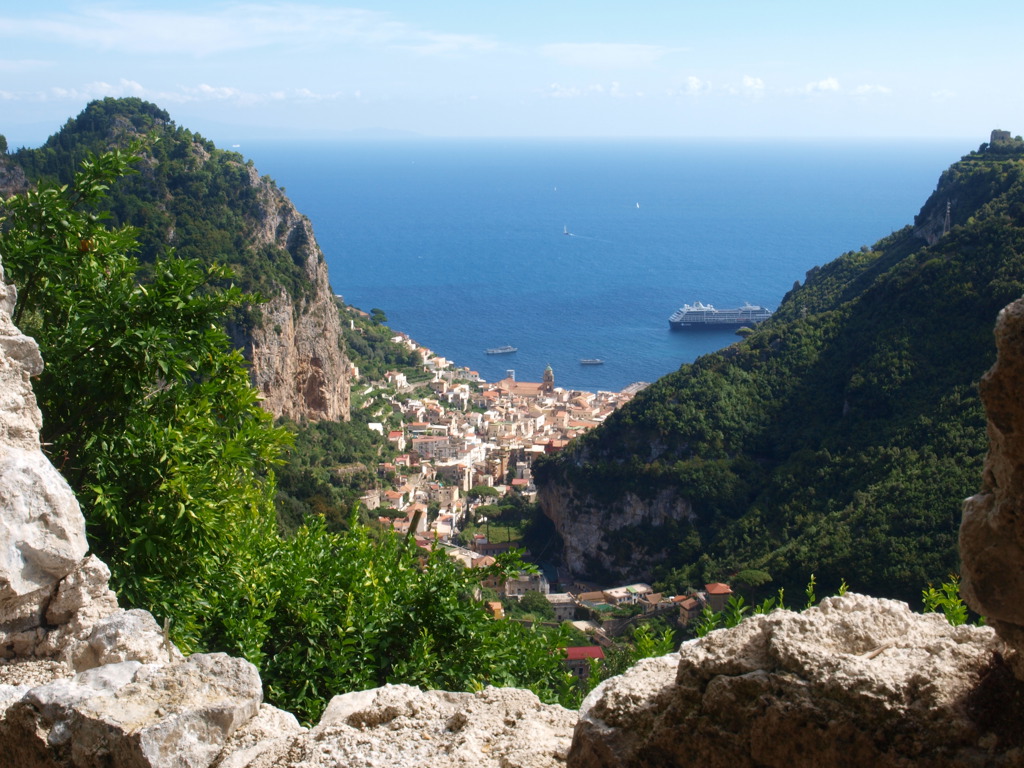Uitzicht op het kustplaatsje Capri aan de Amalfikust, met steile kliffen en een cruiseschip op zee.