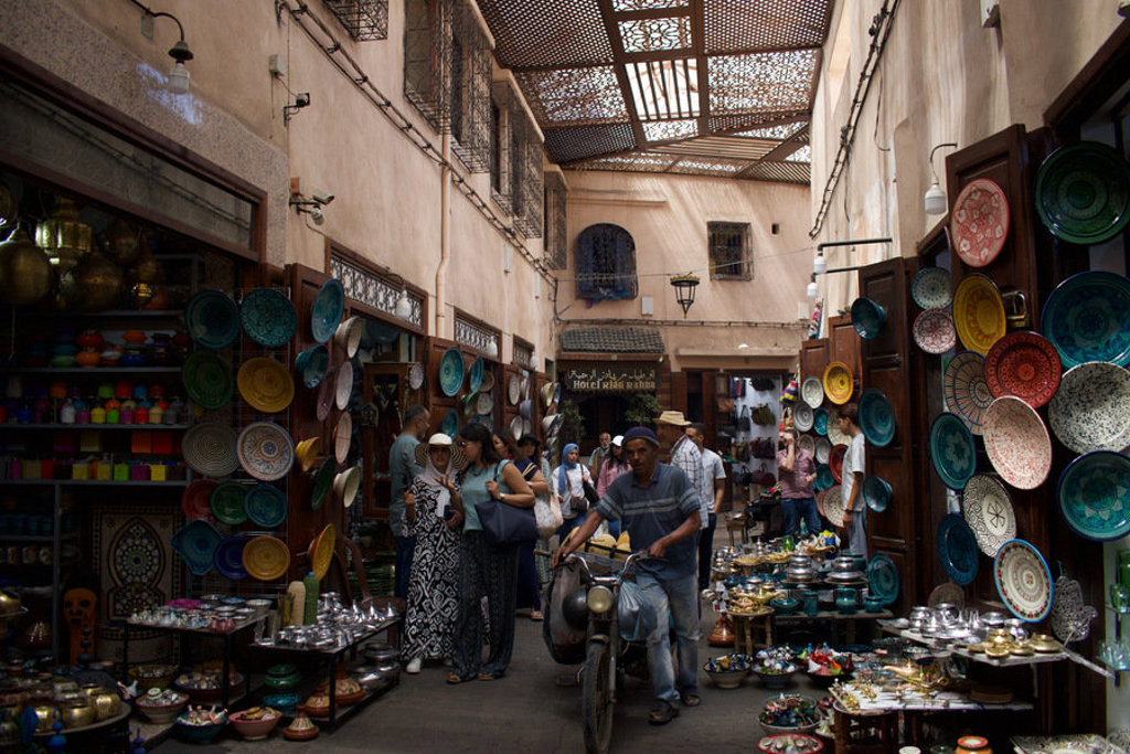 Drukke souk in Marokko met kleurrijk aardewerk en winkeltjes, tijdens groepsrondreis Marokko Hoogtepunten.