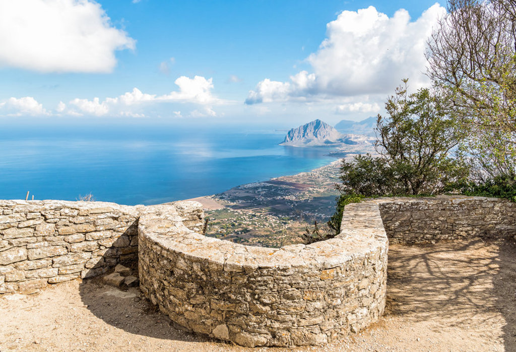 Uitzichtpunt met stenen muurtje en panorama over de kust en bergen van West-Sicilië, Italië.