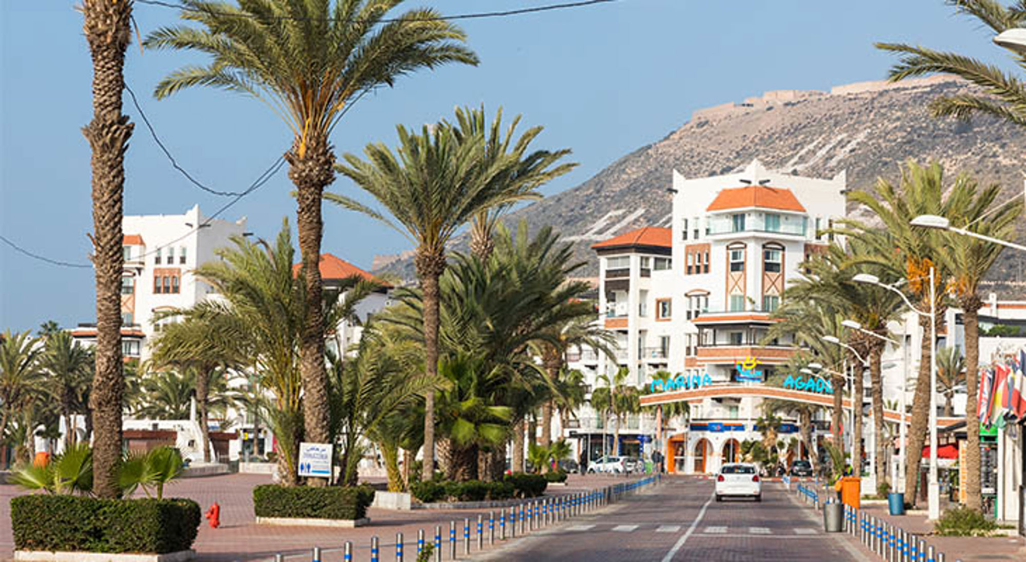 Palmenboulevard bij Marina Agadir met witte gebouwen en bergen op de achtergrond, Marokko.