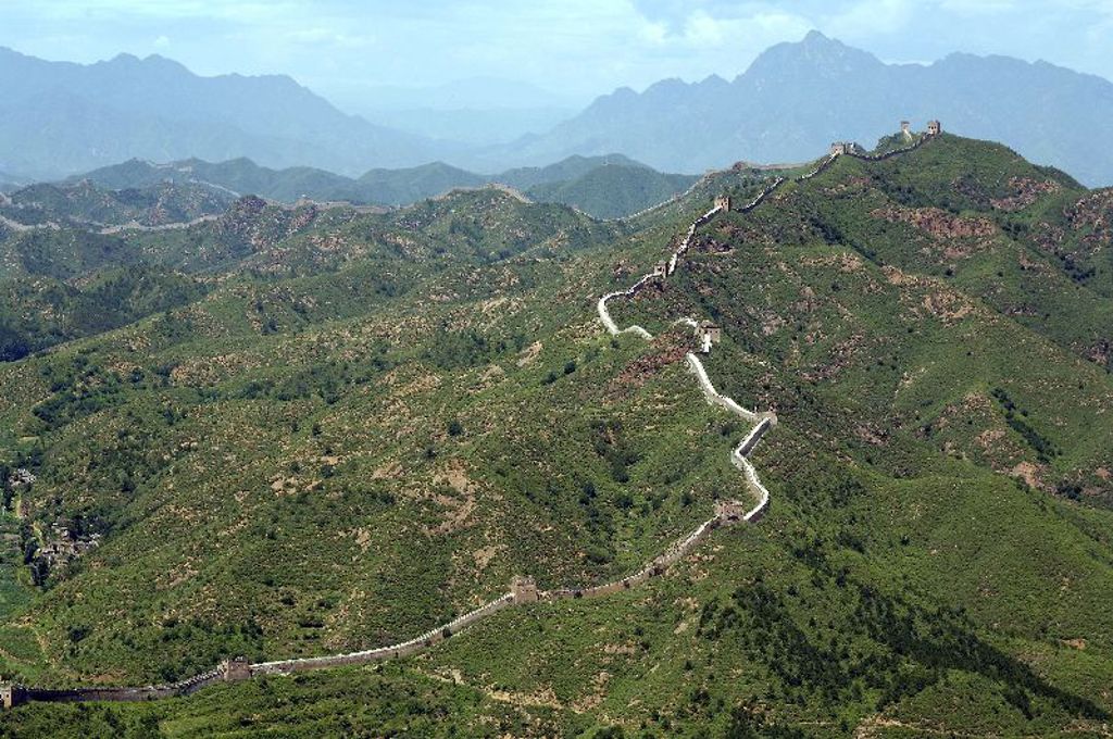 De Chinese Muur slingert over groene bergen tijdens een familiereis China.