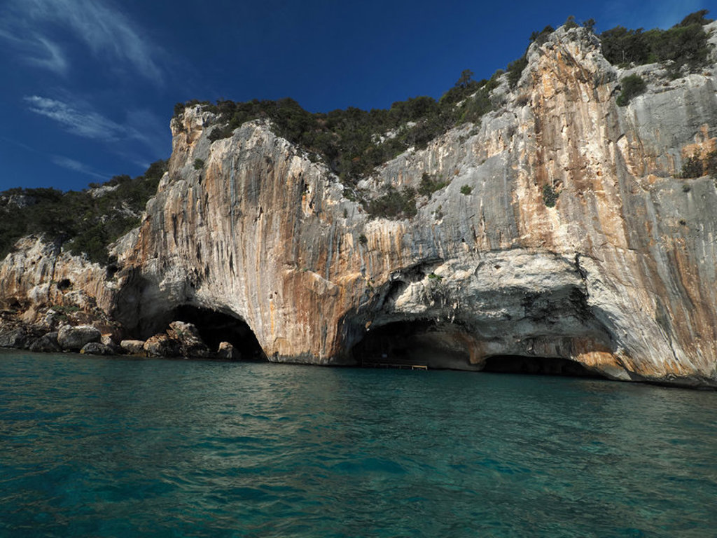Kalkstenen kliffen met grotten aan de kust van Sardinië, Italië, met helderblauw zeewater.