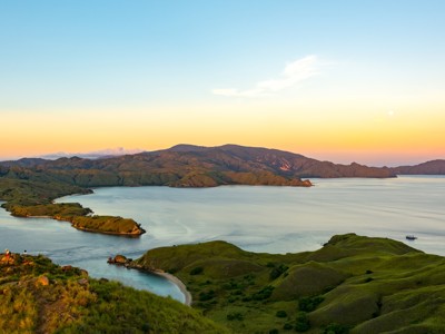 Panoramisch uitzicht over Komodo National Park met groene heuvels en baaien bij zonsondergang.