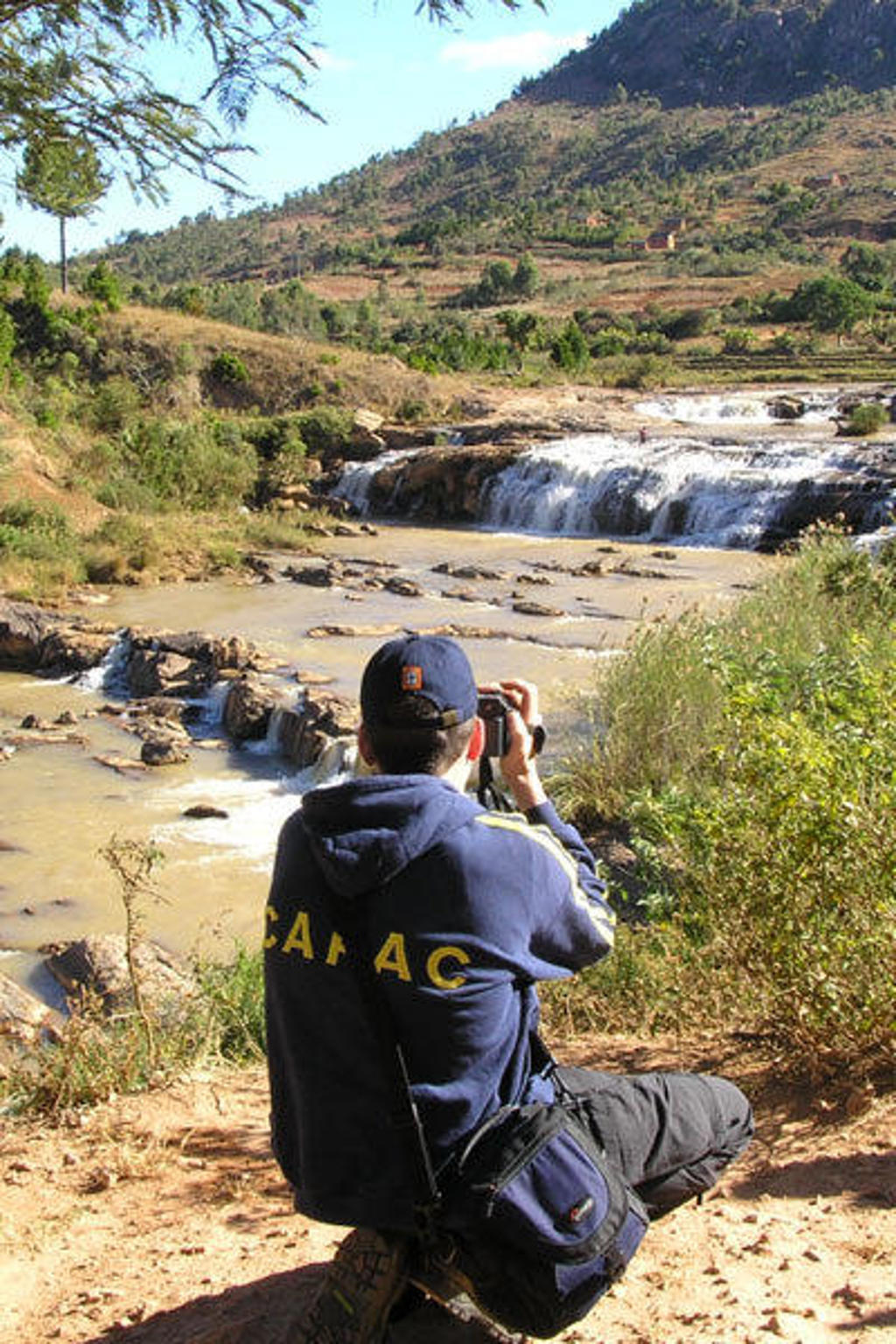 Reiziger fotografeert watervallen en rivier in het heuvelachtige landschap van Madagascar.