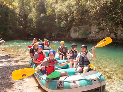 Rafting op een helderblauwe rivier in Noord-Griekenland, met groep in raftboot en helmen.