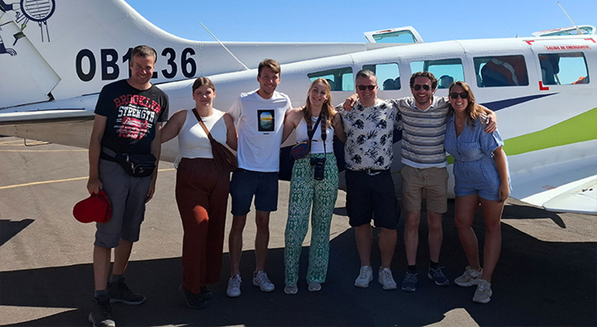 Nazca Groep reizigers poseert voor een klein propellervliegtuig op de luchthaven.