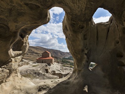 Uitzicht vanuit een rotsgrot op de Uplistsikhe-grottenstad en een kerk in Georgië.