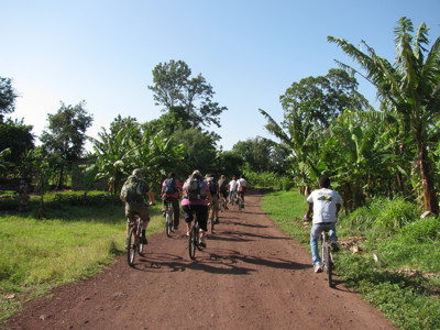 Fietstocht over een rode zandweg langs bananenbomen in Tanzania tijdens de route Kenia, Tanzania en Zanzibar.