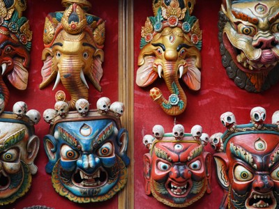 Traditionele Nepalese maskers in felle kleuren, uitgestald op een rode achtergrond tijdens de Route Nepal.