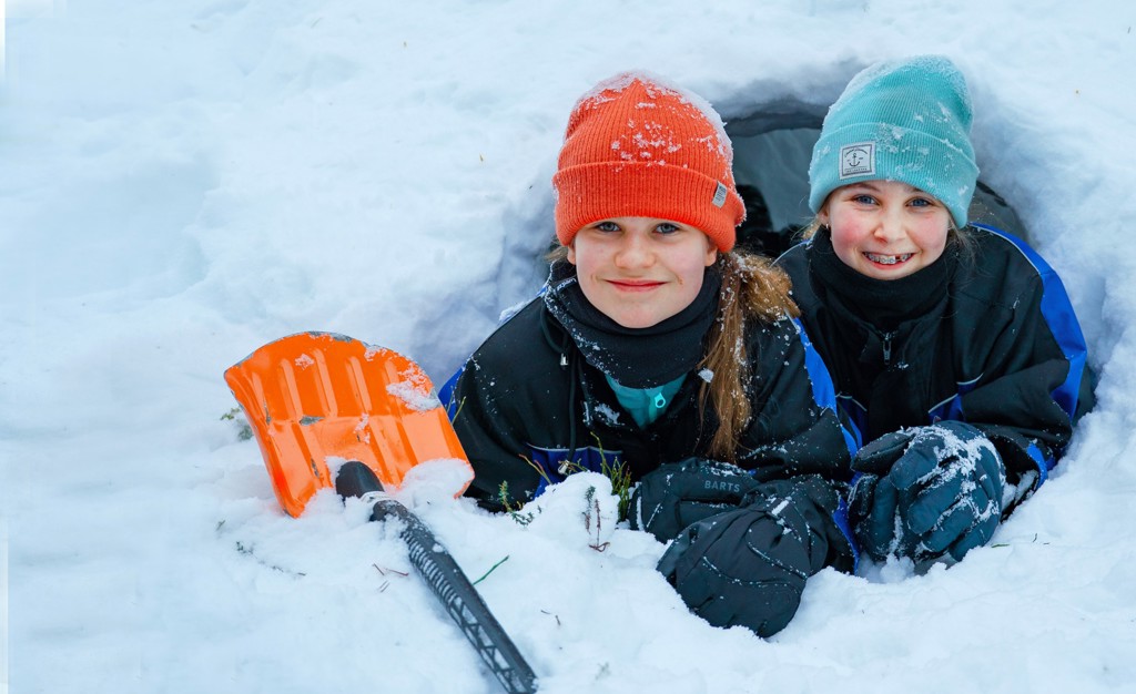 Kinderen bij een sneeuwhol in Lapland tijdens een winterse familiereis, met schep in de sneeuw.
