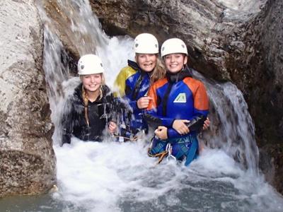 Canyoning in de Vésubie-vallei bij Route Mercantour & Vésubie: drie deelnemers in wetsuit en helm bij een waterval.