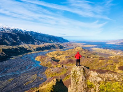 Wandelaar kijkt uit over de Thórsmörk-vallei en een vlechtende rivier in IJsland.