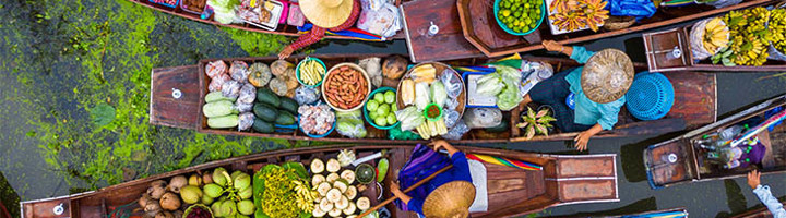 Drijvende markt in Thailand met boten vol verse groenten, fruit en kruiden.