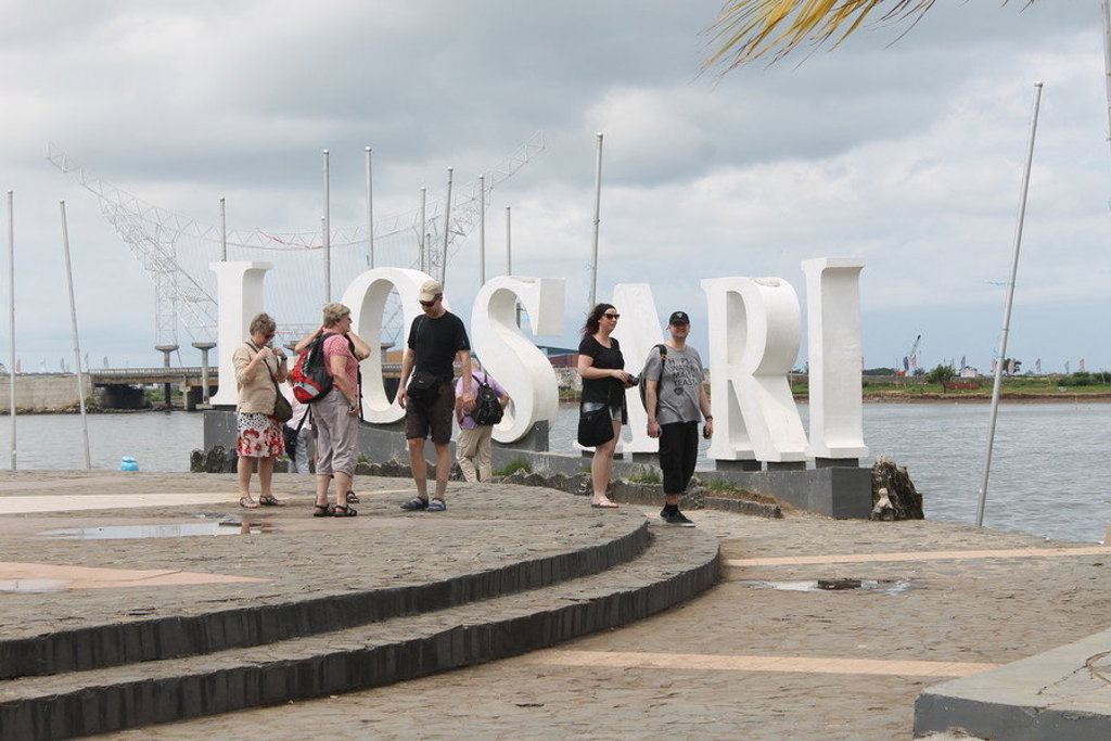 Reizigers bij het grote LOSARI-bord aan de boulevard van Makassar, Sulawesi.