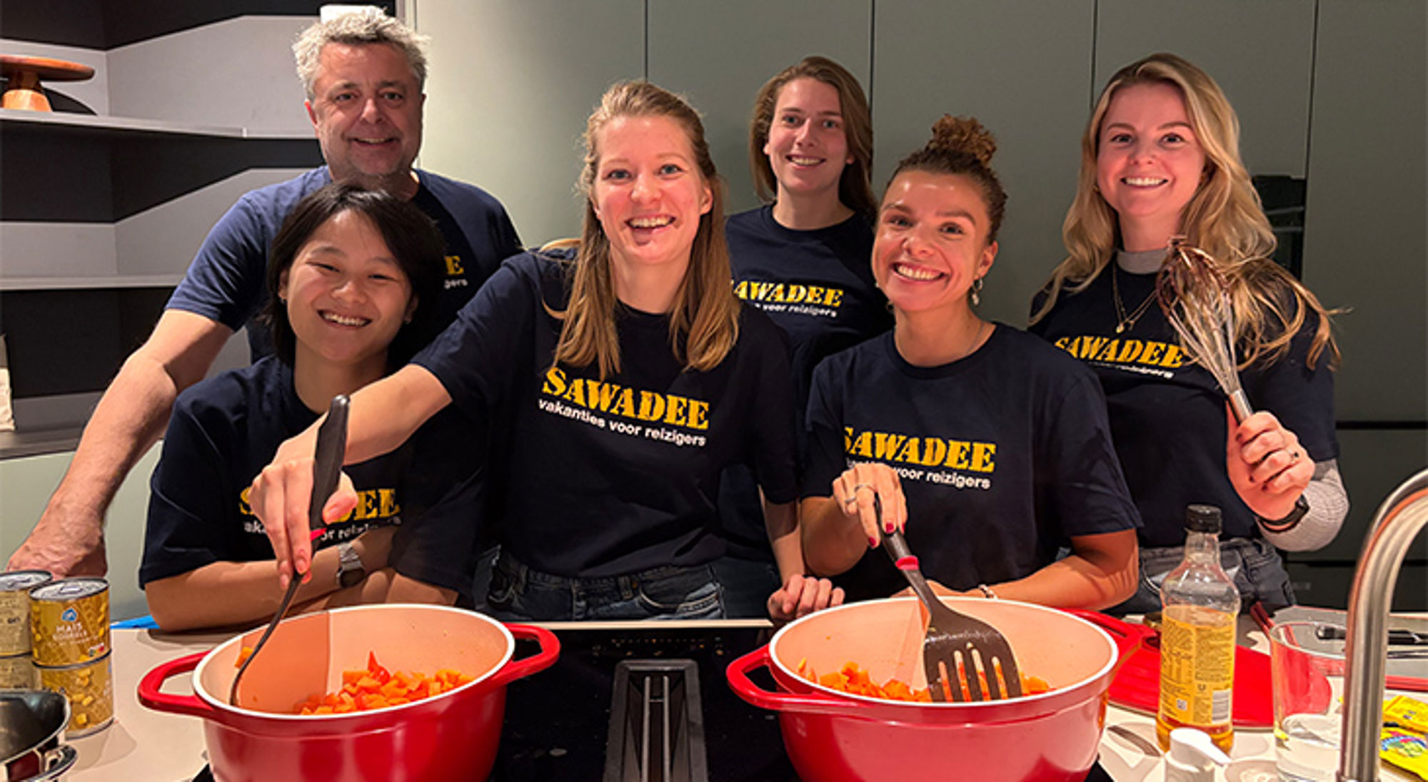 Ronald McDonald Huis Amsterdam SAWADEE-team kookt samen in de keuken met pannen op het fornuis en kookgerei in de hand.