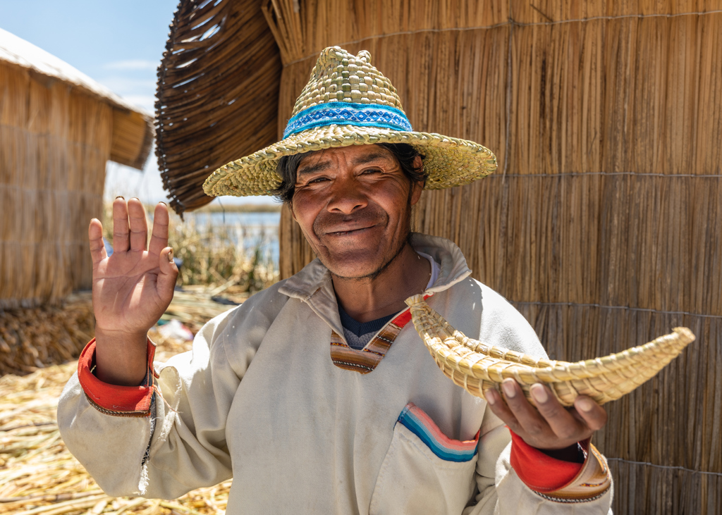 Man met strohoed bij rieten huisjes op het Titicacameer in Peru, tijdens 22-35ers groepsrondreis.