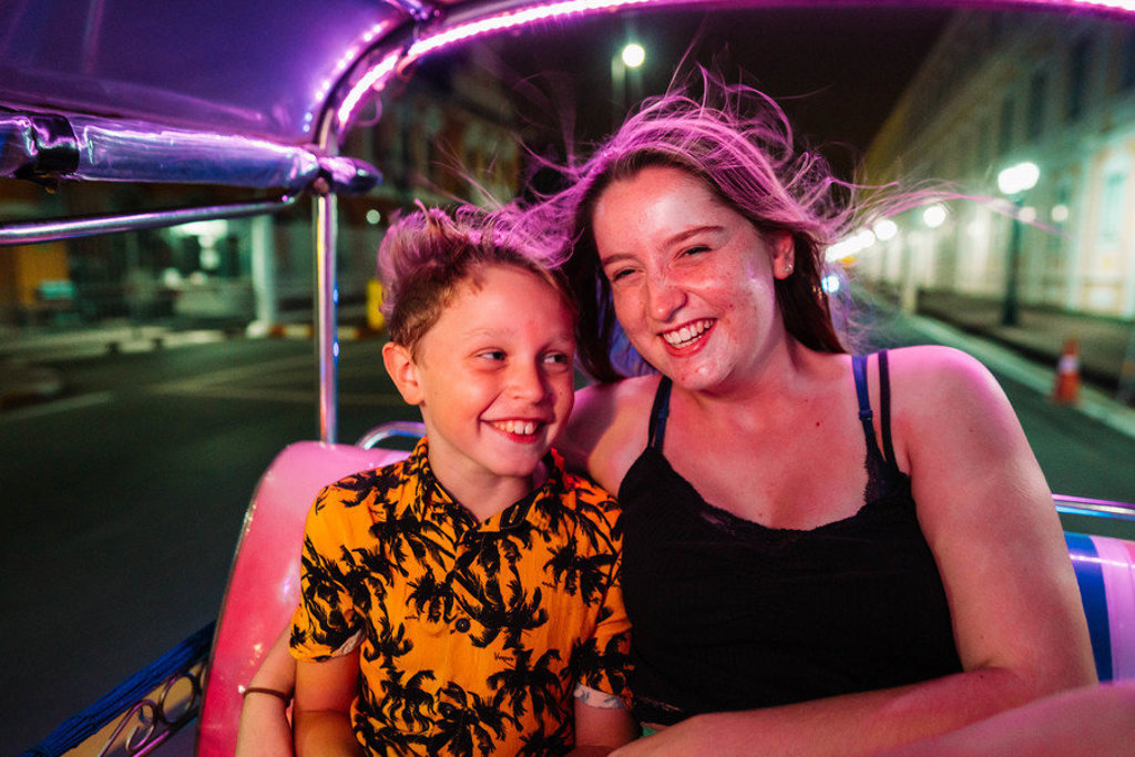 Moeder en zoon lachen in een tuktuk tijdens een familiereis Thailand in de avond.