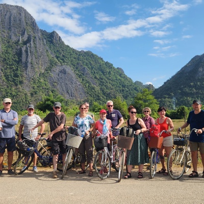 Groepsrondreis Laos & Cambodja: reizigers met fietsen voor karstbergen in het groene landschap.