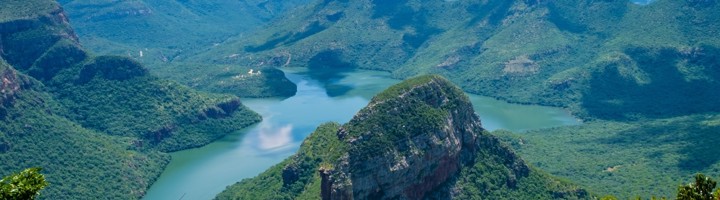 Uitzicht vanaf Graskop over de Blyde River Canyon met rivier, groene bergen en rotsformaties onder blauwe lucht.
