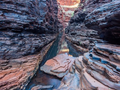 Smalle kloof met rotswanden en helder water in Karijini National Park, West Australië.