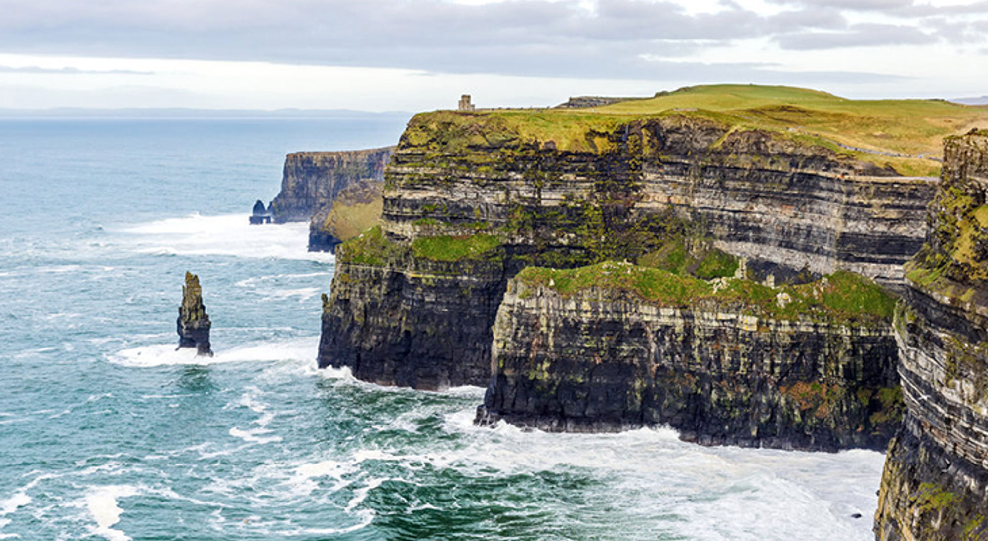 Uitzicht op de Cliffs of Moher aan de Ierse westkust met steile kliffen, zee en een rots in het water.