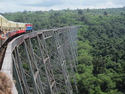 Trein over de Gokteik-viaductbrug in Myanmar, met uitzicht op groene heuvels en jungle.