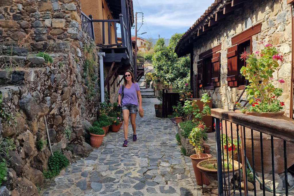 Wandelaar in smalle straat met stenen huizen en bloempotten tijdens wandelvakantie op Cyprus.