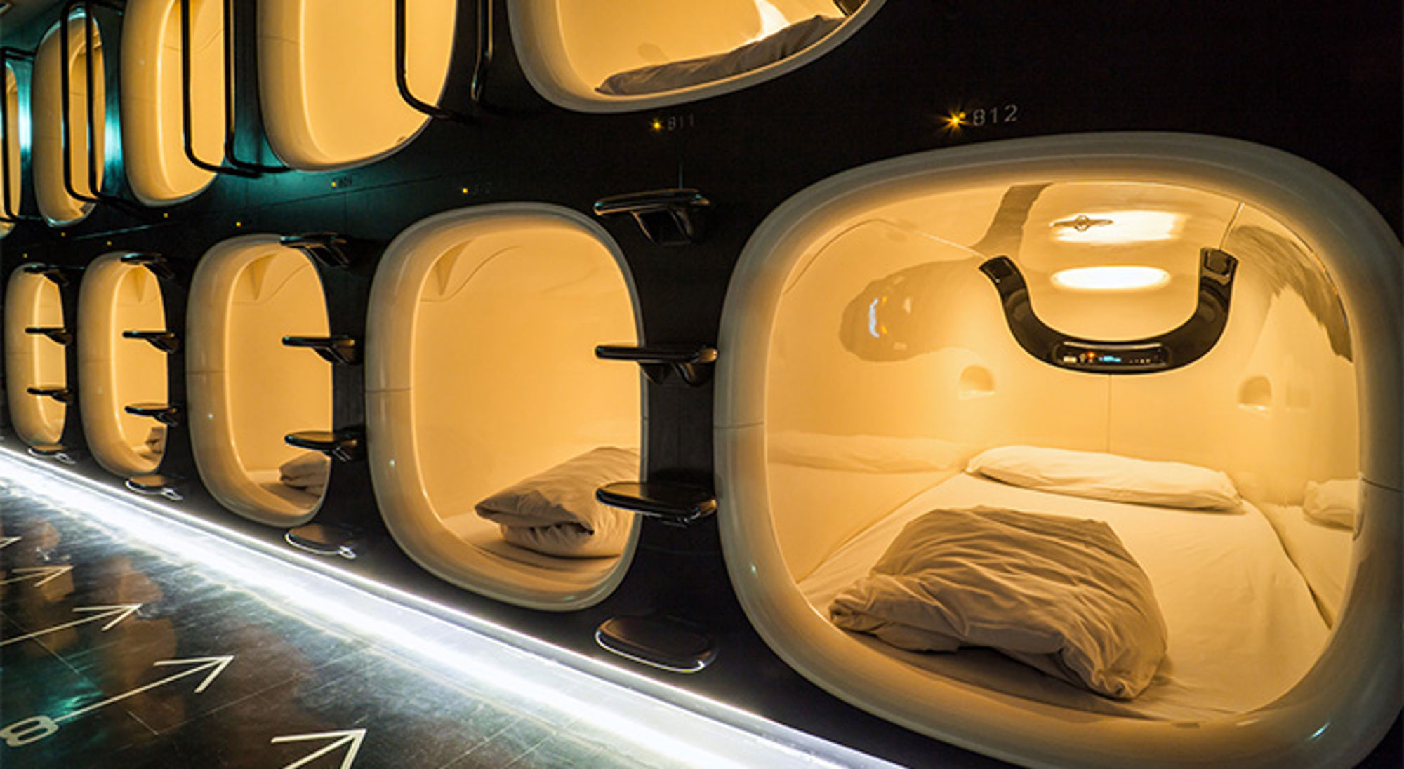 Capsulehotel Verlichte slaapcapsules in een capsulehotel, met opgemaakte bedden en een gangpad.