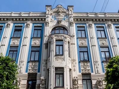 Jugendstilgevel in Riga met blauwe tegels, sierlijke reliëfs en balkon.